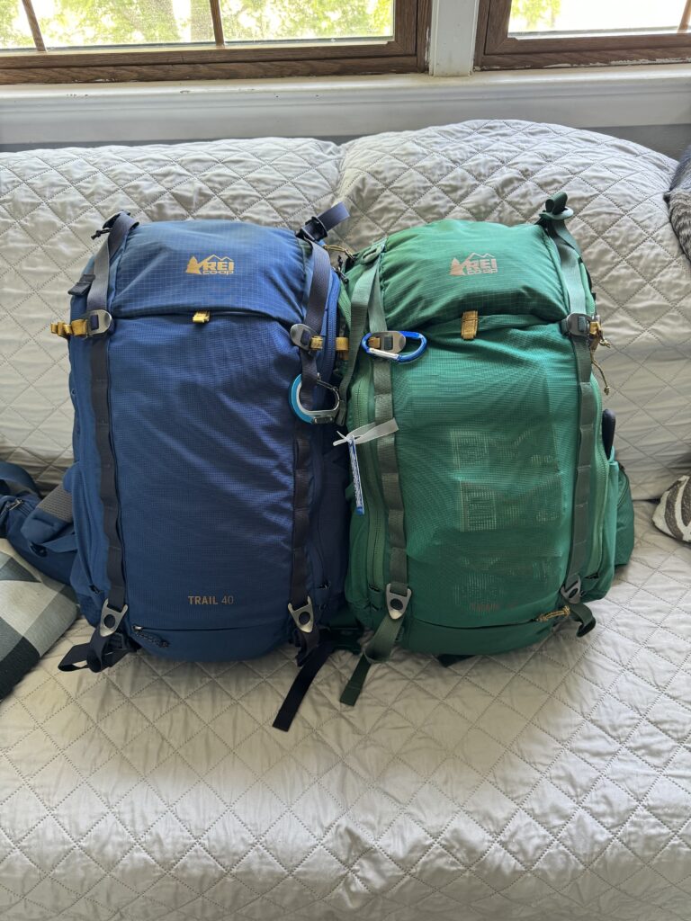 A pair of REI Trail 40L backpacks next to each other, one blue and one green.